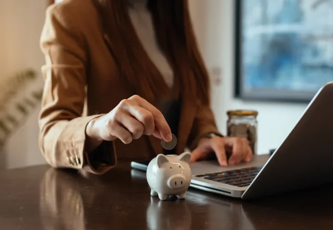 Woman saving money with piggy bank and laptop